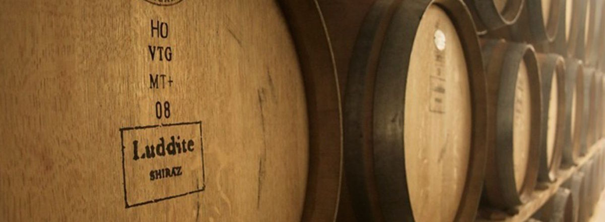 Nahaufnahme von Barriquefässern im Keller der Luddite Winery, mit sichtbarer Fassprägung.