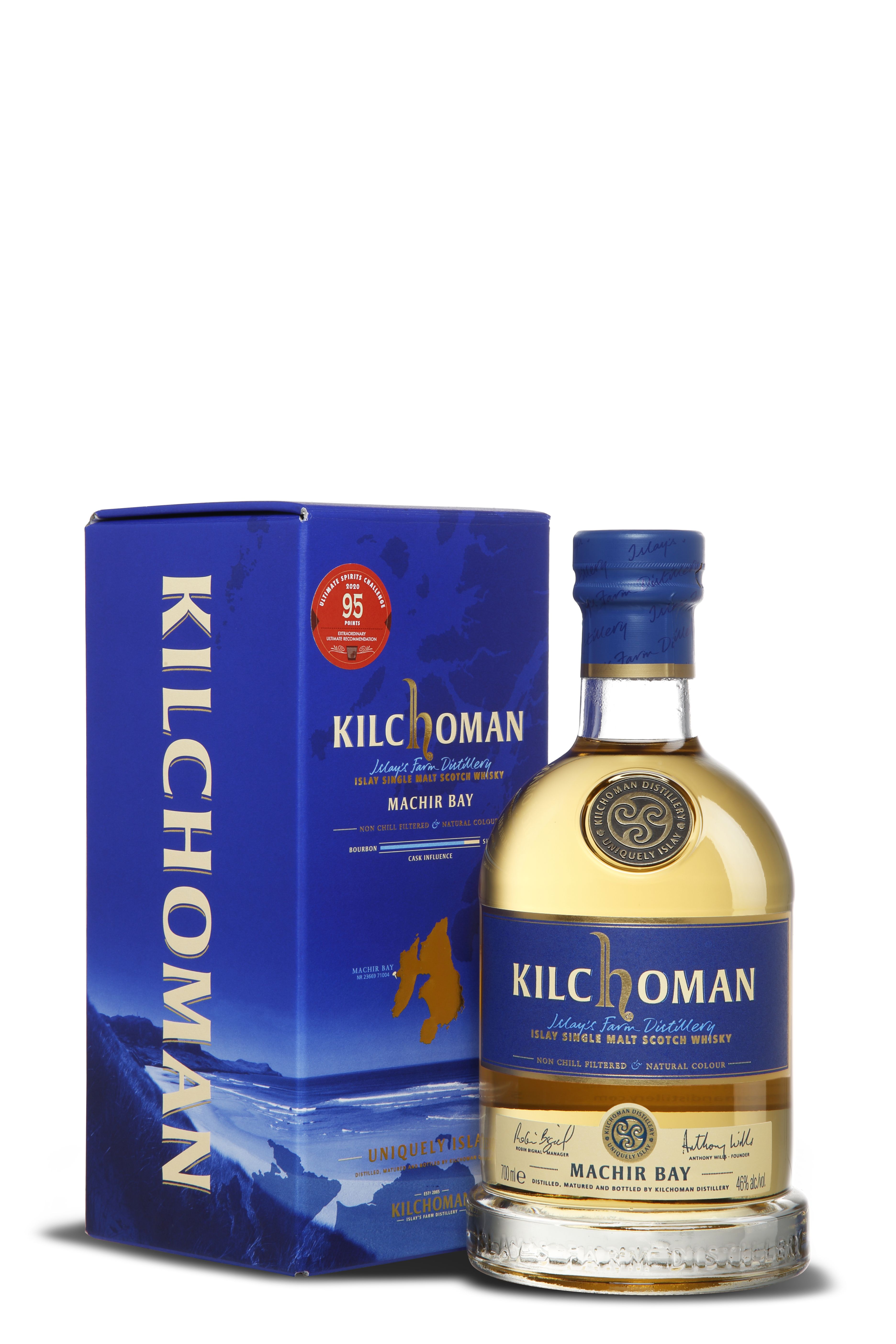 Die Flasche Kilchoman Machir Bay steht vor ihrer blauen Verpackung. Das helle, goldene Destillat ist im Glas sichtbar. Das blaue Etikett und die Verpackung zeigen den Namen Kilchoman, goldene Schrift und eine Küstenlandschaft im Hintergrund.