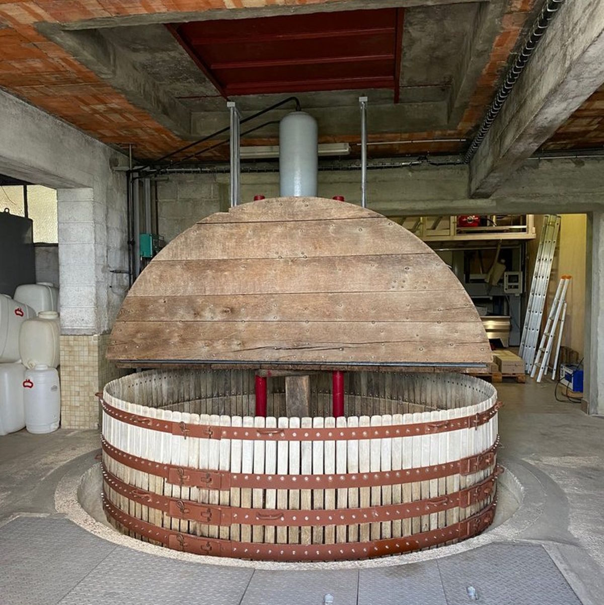 Traditionelle vertikale Weinpresse aus Holz und Metall in einem Weingutkeller.