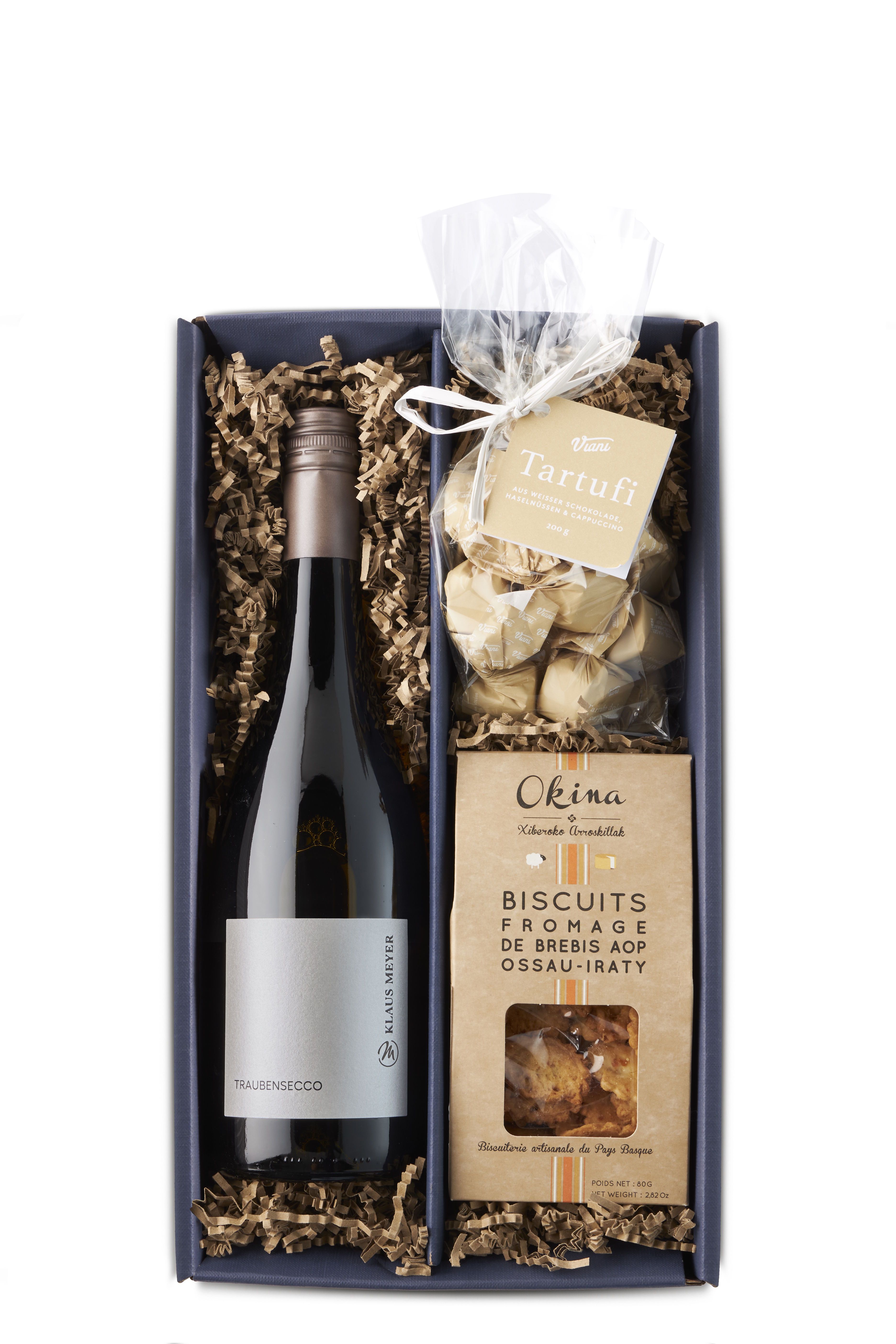 Elegante Geschenkbox in schwarz mit naturfarbenem Füllmaterial. Enthält eine alkoholfreie Traubensecco-Flasche, verpackte Trüffelpralinen im Klarsichtbeutel mit Schleife sowie eine Packung Käsegebäck in naturfarbener Papierverpackung