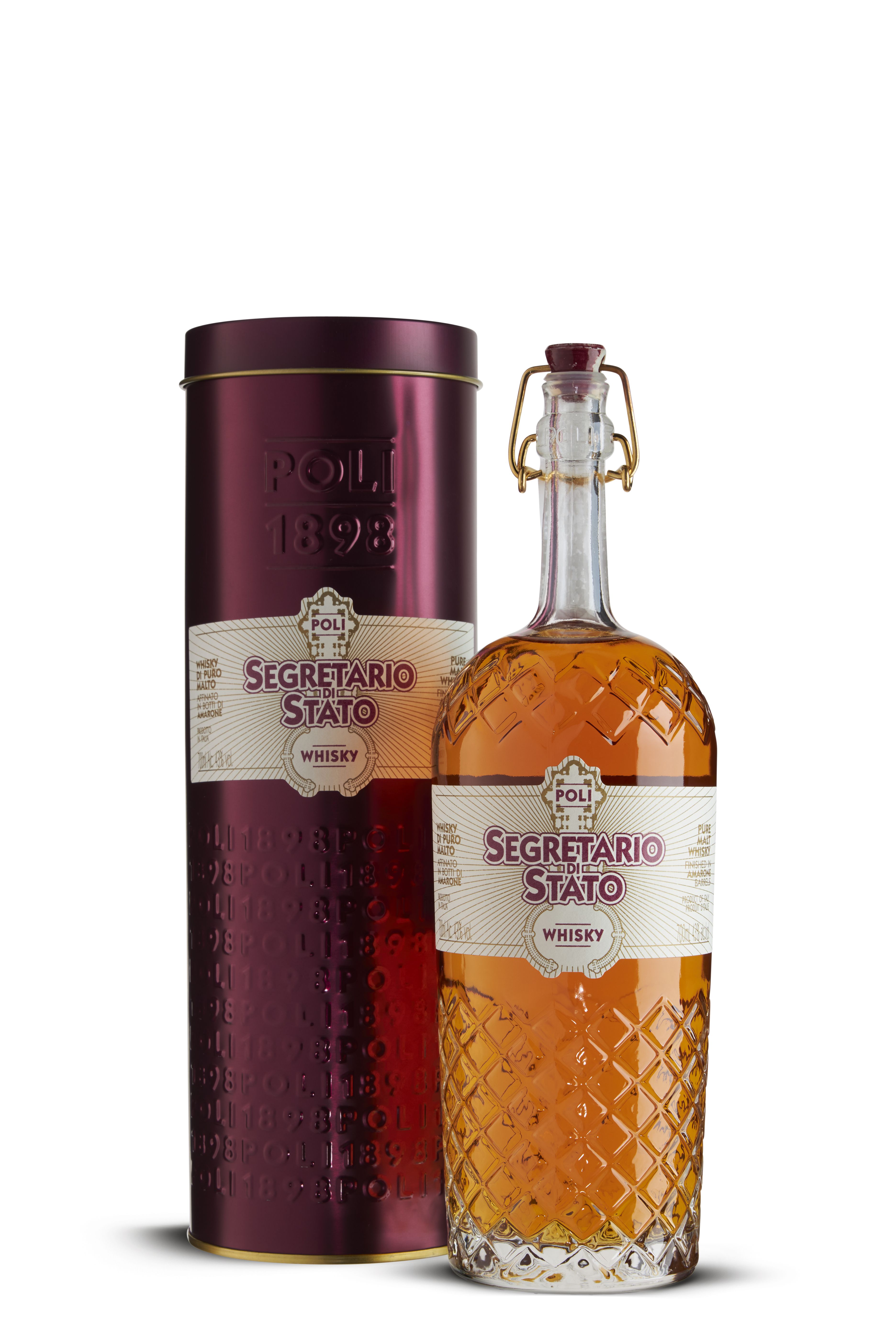 Flasche mit Whisky „Segretario di Stato“ von Poli, klare Flasche mit Rautenmuster. Hellbrauner Whisky mit cremeweißem Etikett und lila Schrift. Dazu passender Metallbehälter in dunklem Lila mit Prägedruck „POLI 1898“.