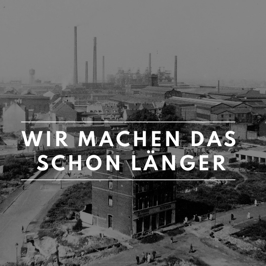 Historische Schwarzweiß-Aufnahme des Bochumer Industriegebiets mit rauchenden Schornsteinen und Gebäuden, überlagert von dem Schriftzug „Wir machen das schon länger“