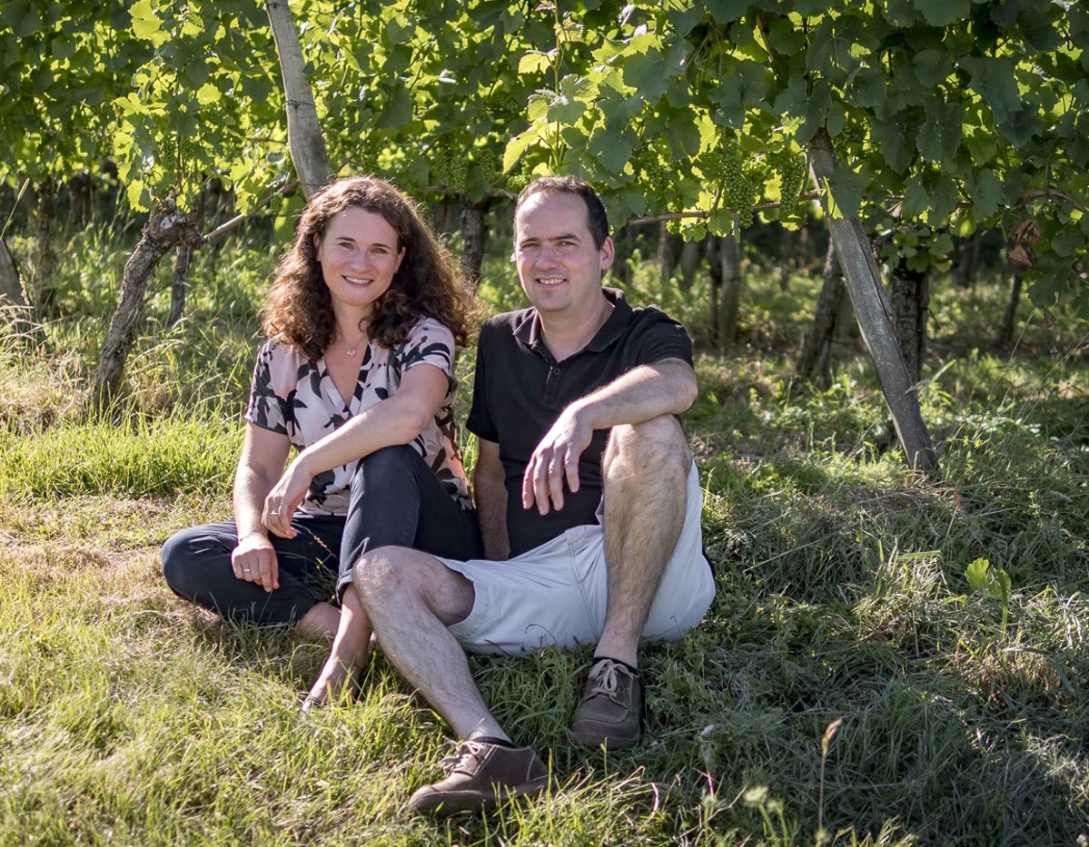 Winzerpaar sitzt gemeinsam zwischen den Reben in einem Weinberg