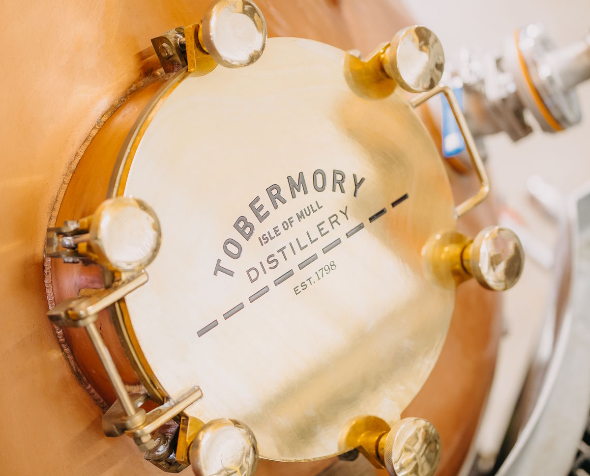 Nahaufnahme eines glänzenden Messingdeckels an einer Kupferbrennblase in der Tobermory Distillery auf der Isle of Mull mit eingraviertem Logo und Gründungsjahr 1798 – Symbol für traditionelle Whiskyherstellung in Schottland