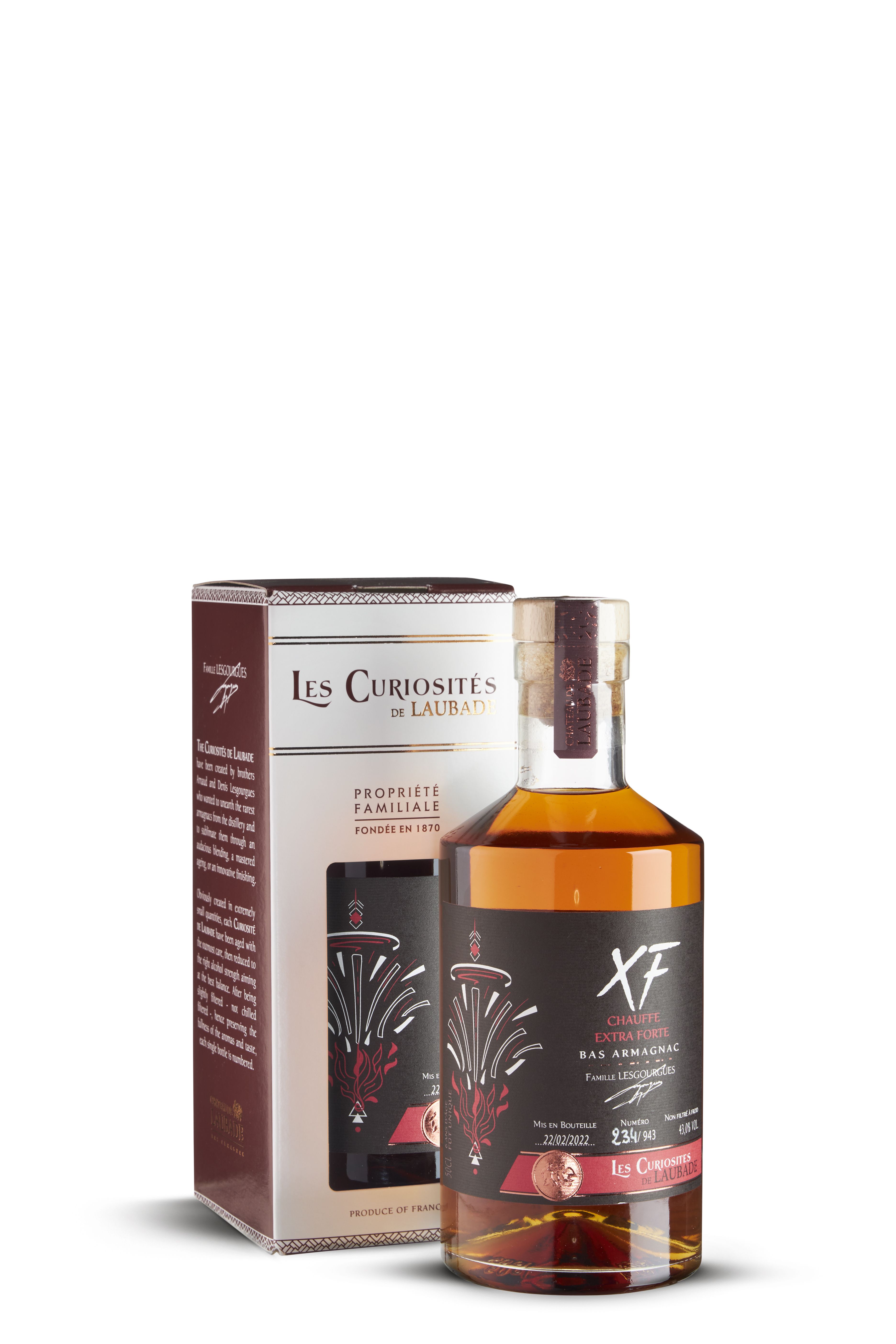 Flasche Armagnac XF von Château de Laubade mit modern gestaltetem, schwarzem Etikett und stilisiertem Flammendekor. Naturkork mit Siegel. Im Hintergrund eine passende Geschenkbox mit identischem Design. Die Flüssigkeit ist warm bernsteinfarben.