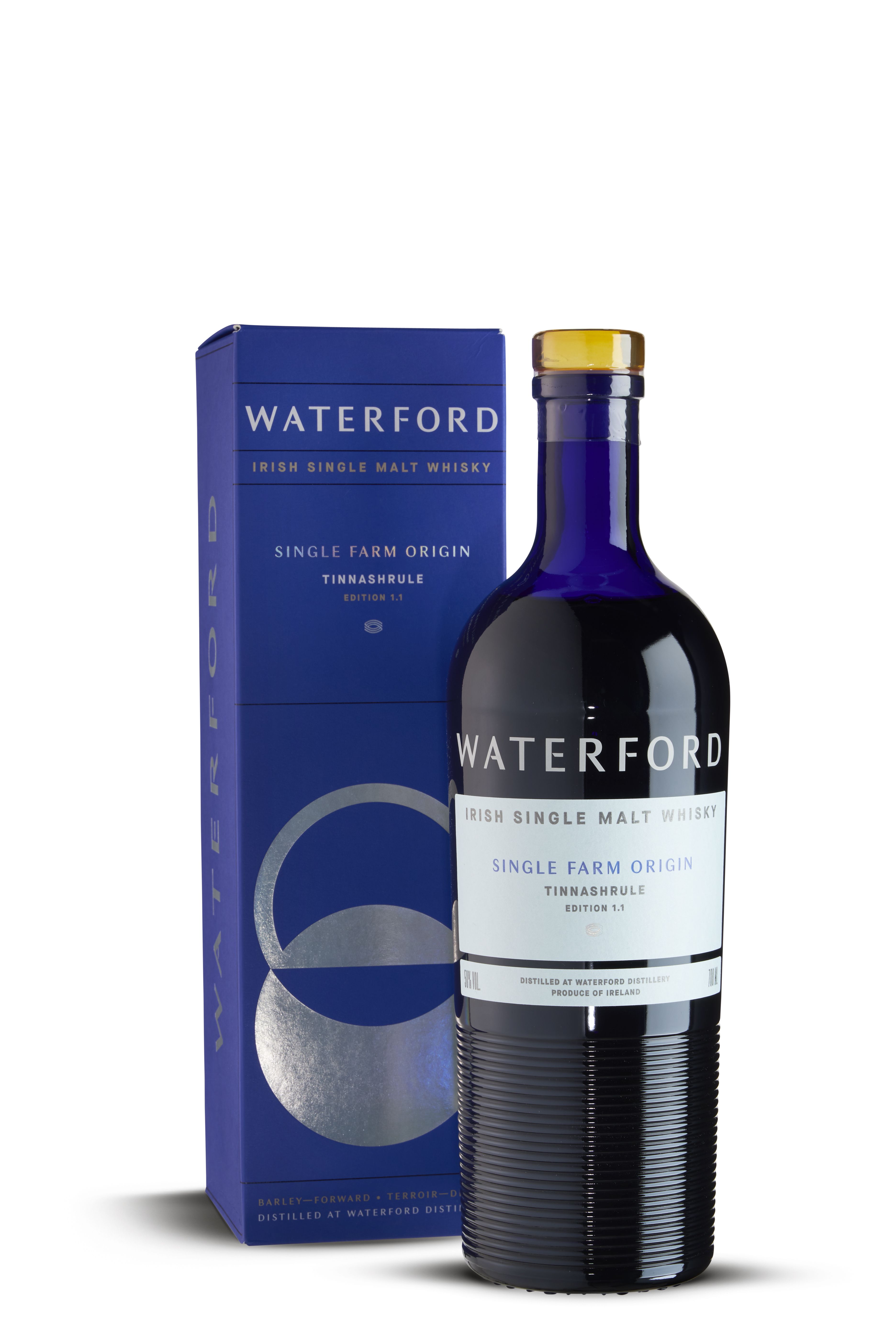 Flasche Waterford Irish Single Malt Whisky „Single Farm Origin Tinnashrule Edition 1.1“ aus dunkelblauem Glas mit silber-weißem Etikett. Daneben blauer Karton mit silbernem Kreis-Design und großem Schriftzug „Waterford“. Edle, klare Präsentation.