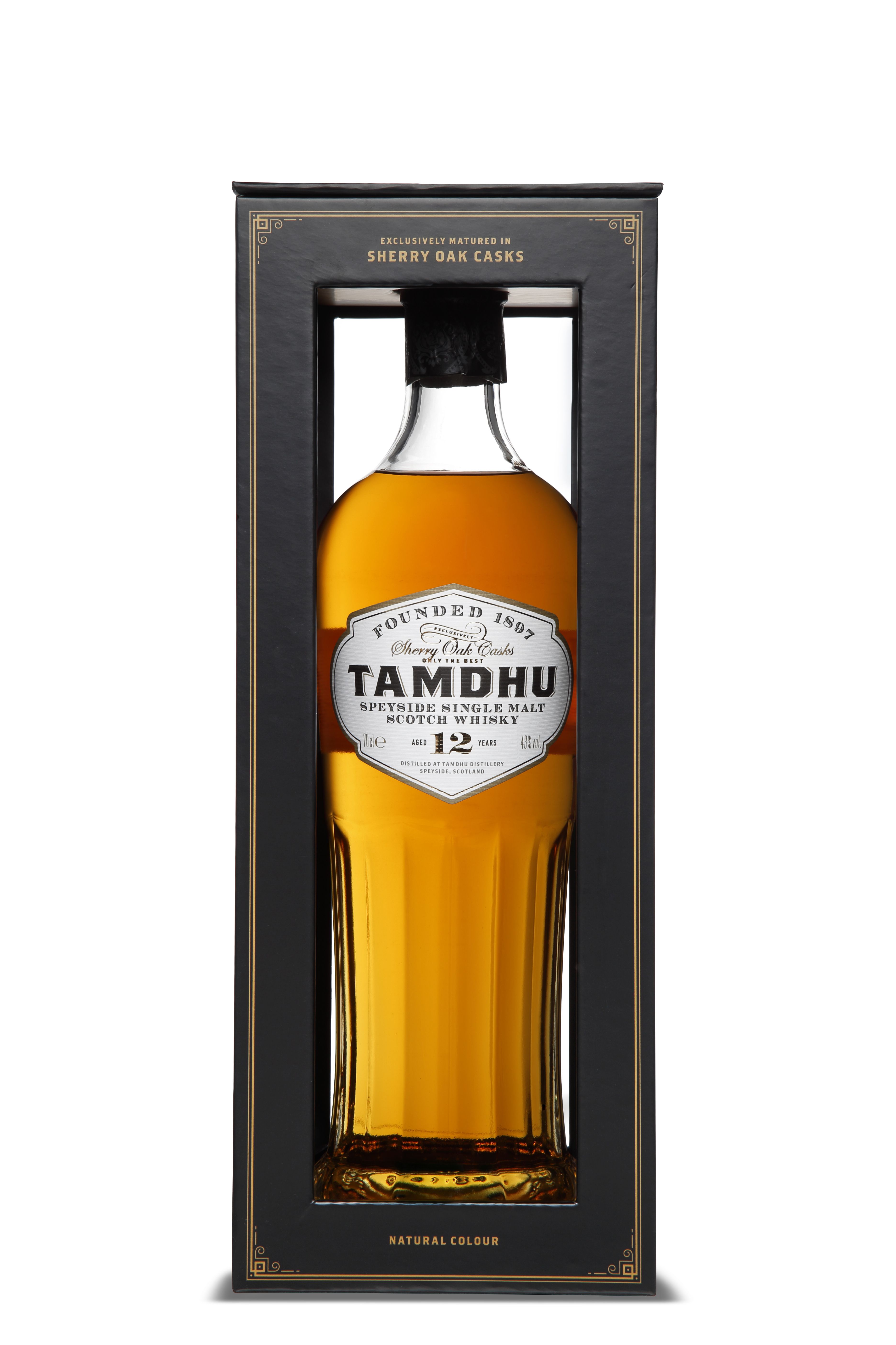Eine klare Flasche mit bernsteinfarbenem Whisky steht in einer schwarzen Verpackung mit Sichtfenster. Das Etikett zeigt „Tamdhu“, „Speyside Single Malt Scotch Whisky“, 12 Jahre alt. Flaschenhals ist schwarz versiegelt, goldfarbene Schrift auf Verpackung.