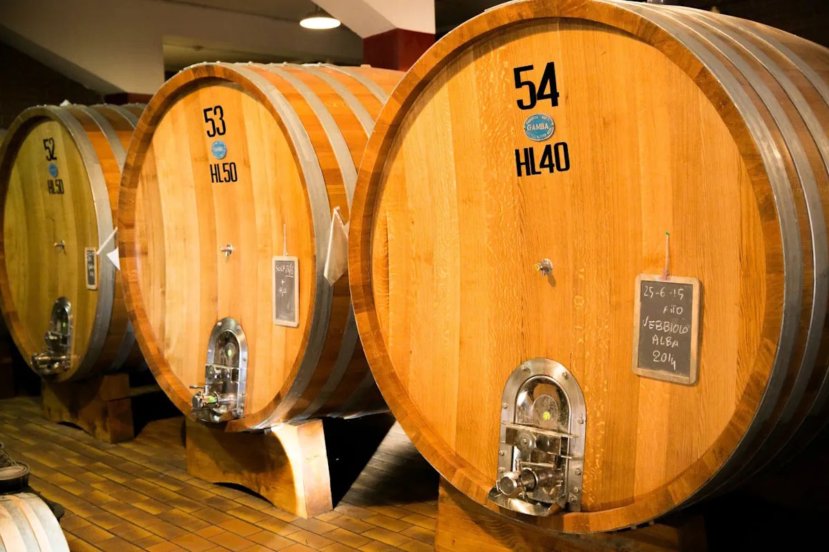 Große Holzfässer zur Weinlagerung in einem Weinkeller, beschriftet mit Fassnummern und Fassungsvermögen