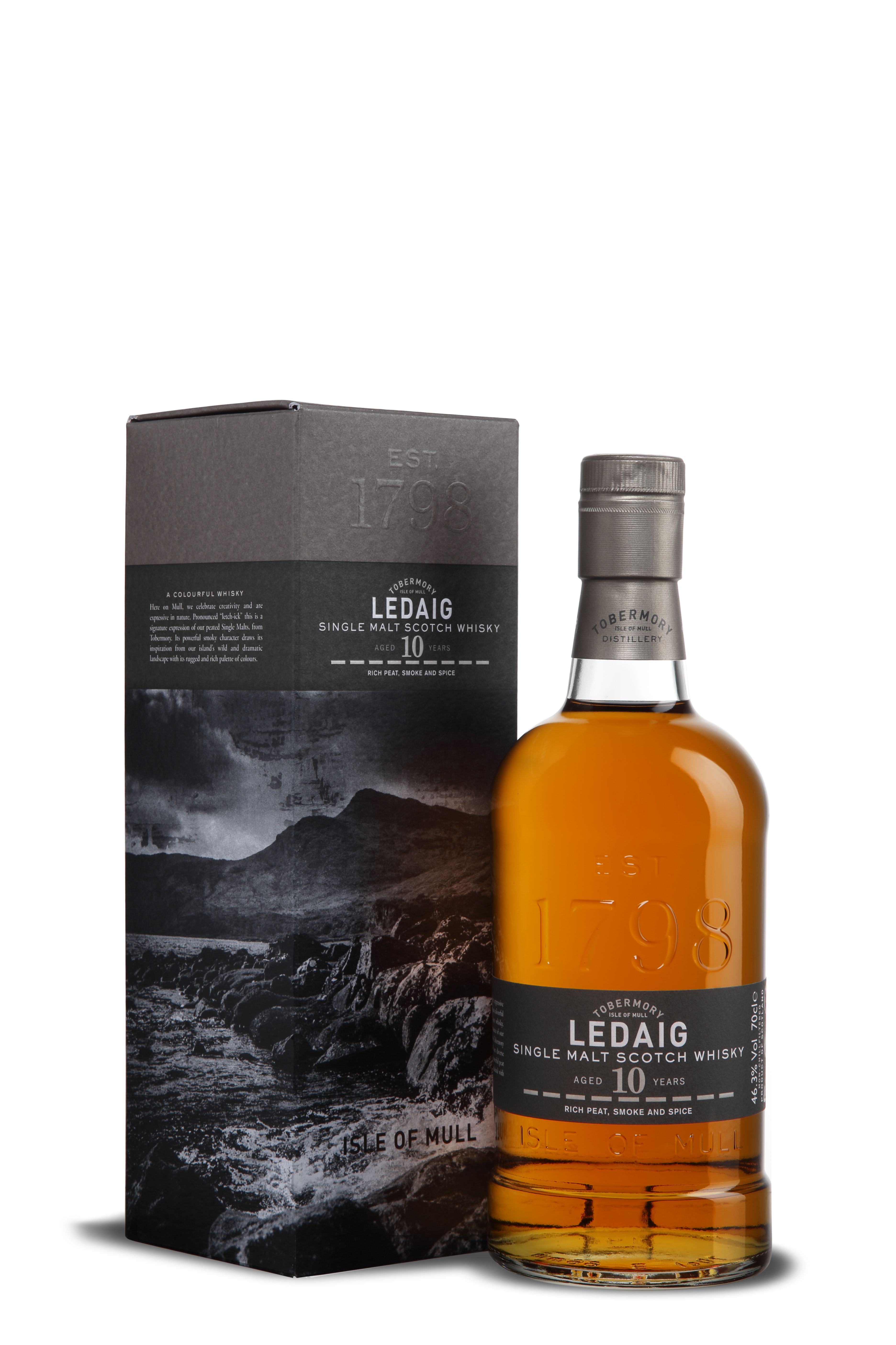 Flasche Ledaig 10 Years mit geprägtem „EST 1798“ und dunkelgrauem Etikett. Der Whisky schimmert in warmem Bernstein. Im Hintergrund eine stilvolle, schwarz-graue Geschenkbox mit stürmischem Küstenmotiv der Isle of Mull und geprägtem Schriftzug.