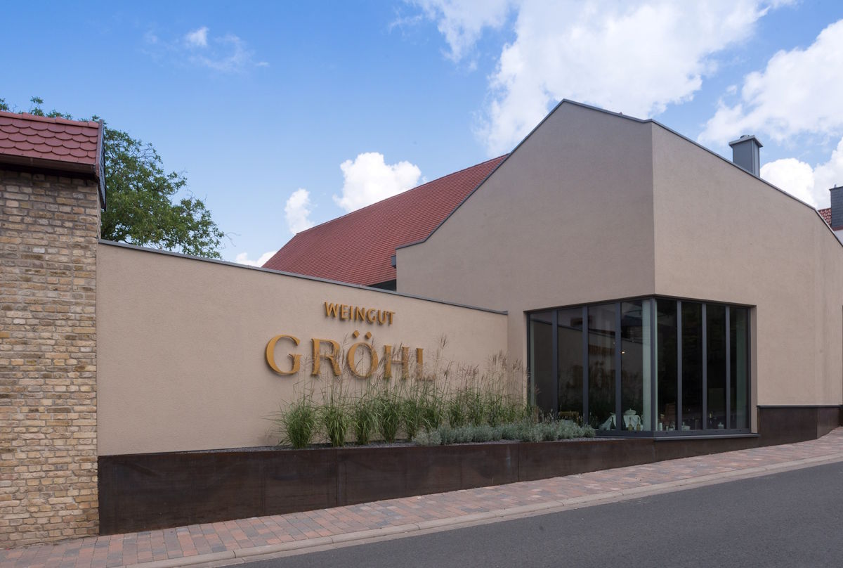 Weingut Gröhl – zeitgemäße Architektur trifft auf rheinhessische Weinkultur Modernes Gebäude des Weinguts Gröhl mit klarer Architektur, großer Fensterfront und goldener Beschriftung an der Fassade