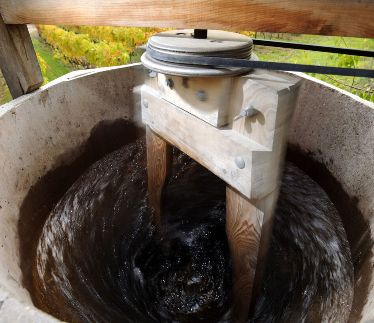 Ein Holzrührwerk erzeugt in einem offenen Bottich einen kräftigen Strudel, vermutlich zur Zubereitung eines biodynamischen Präparats.
