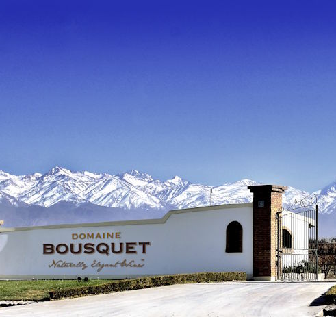 Eingangstor der Domaine Bousquet mit weißer Mauer und Schriftzug, im Hintergrund die schneebedeckten Anden.
